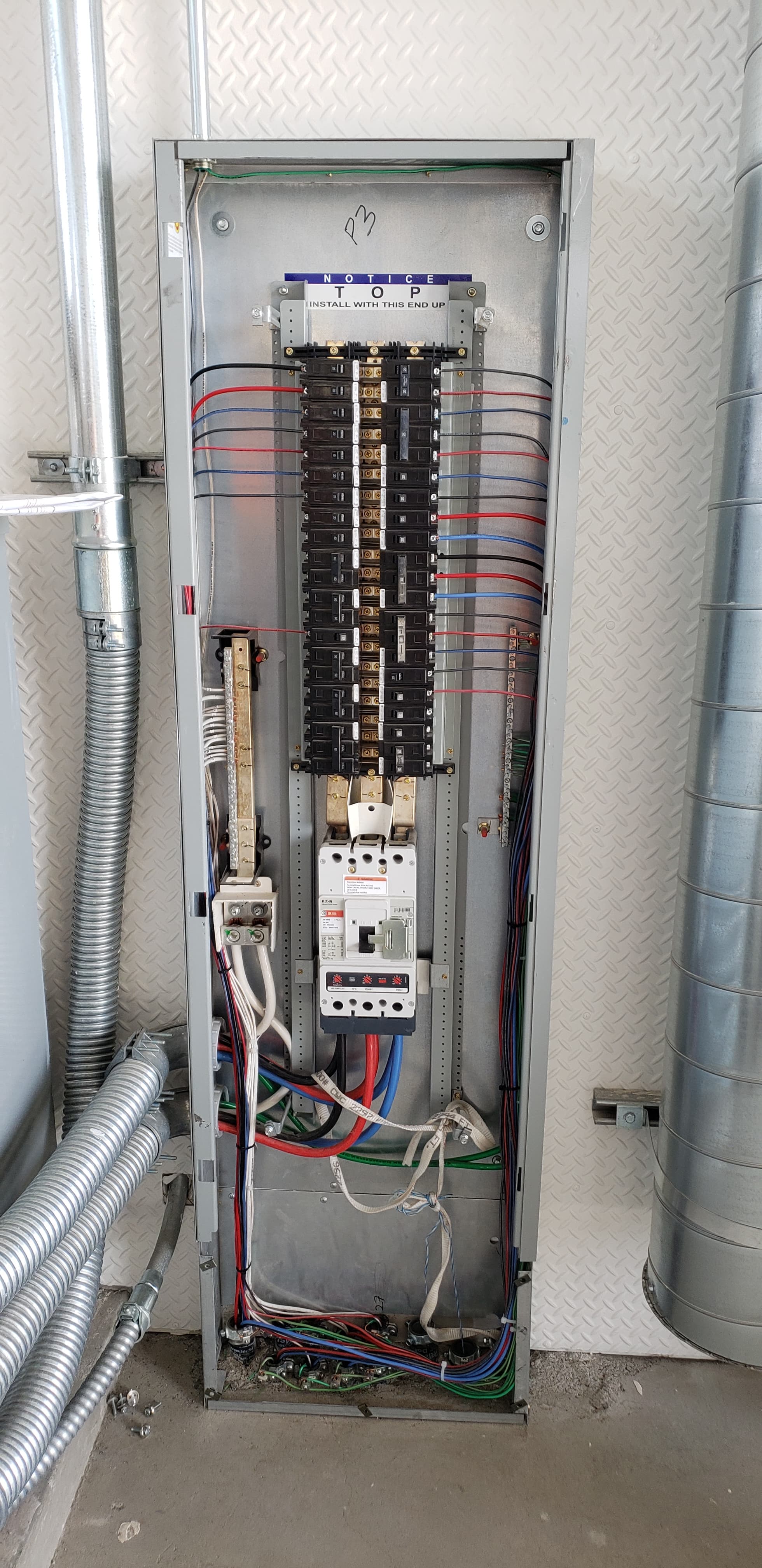 Commercial panelboard interior with a main breaker and neatly combed branch-circuit conductors
