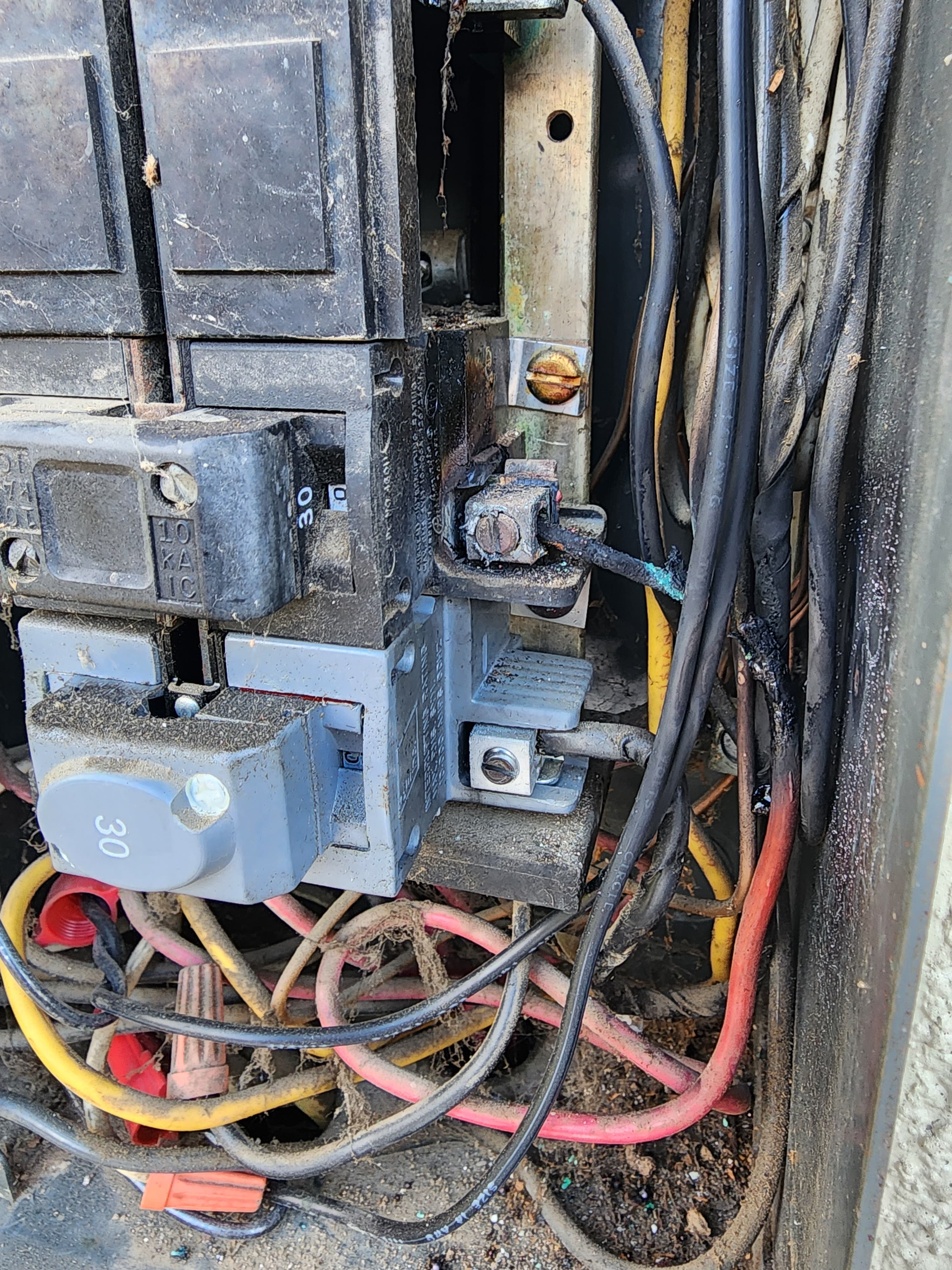 Burned electrical panel with scorched breakers and heat-damaged conductors