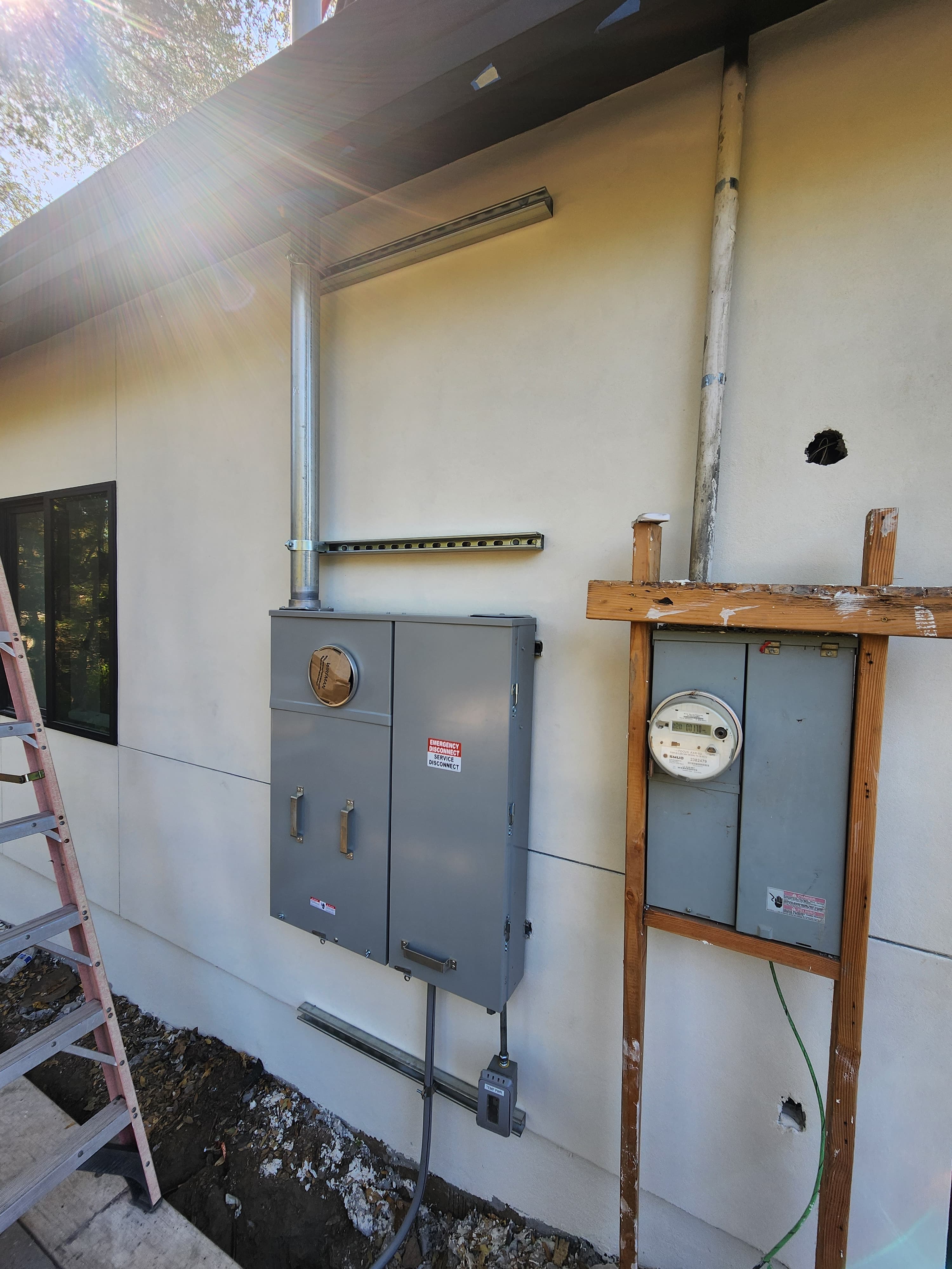 New exterior service disconnect and meter-main with a service mast beside an older utility meter